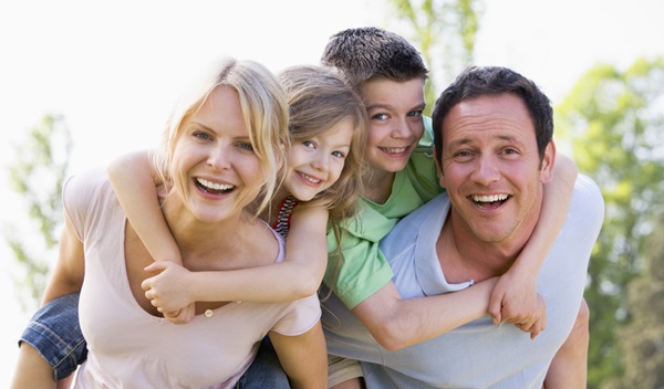 couple-giving-two-young-children-piggyback-rides-smiling